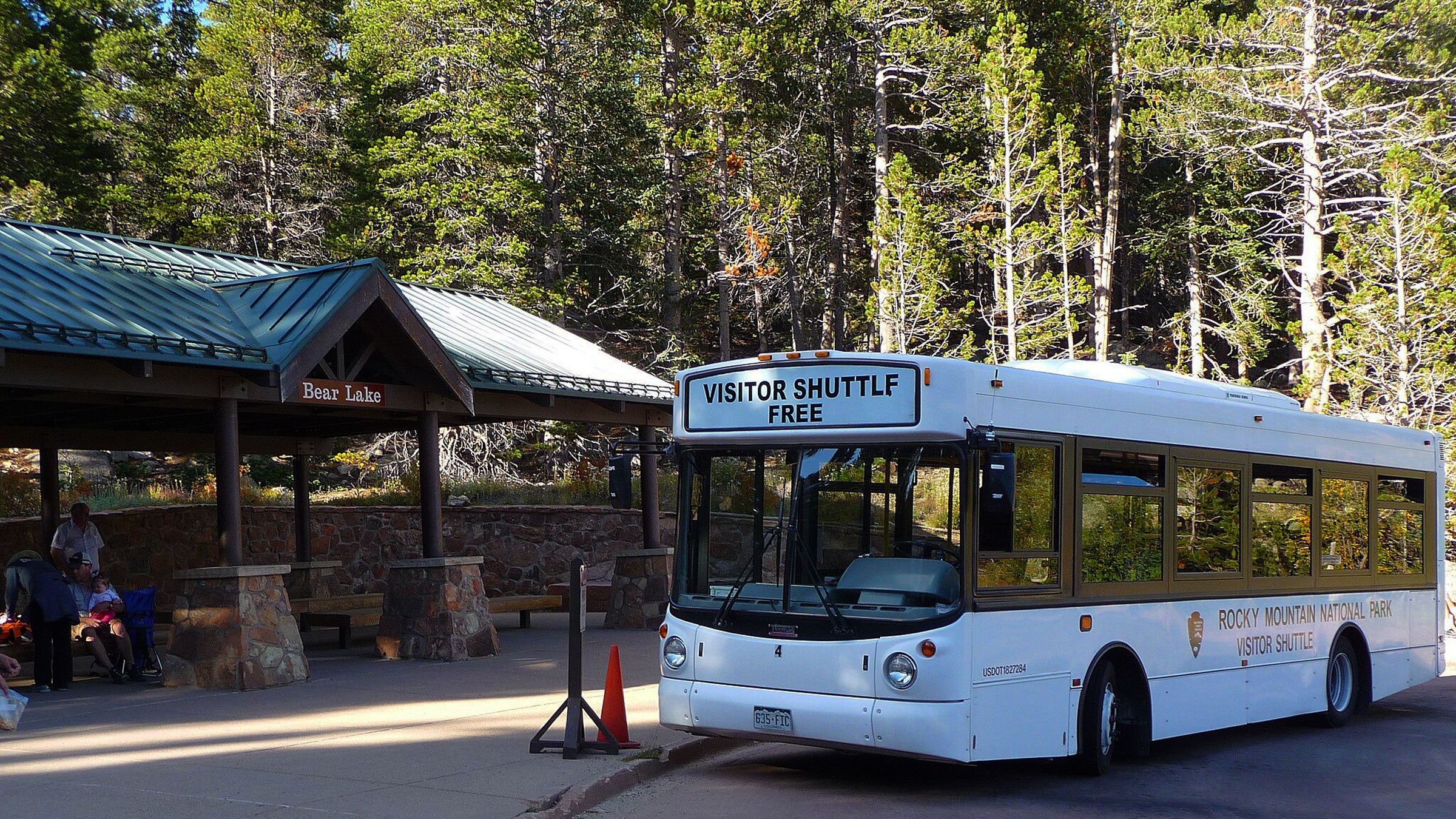 A Rocky Mountain National Park visitor shuttle bus picking up passengers at the Bear Lake stop in the park