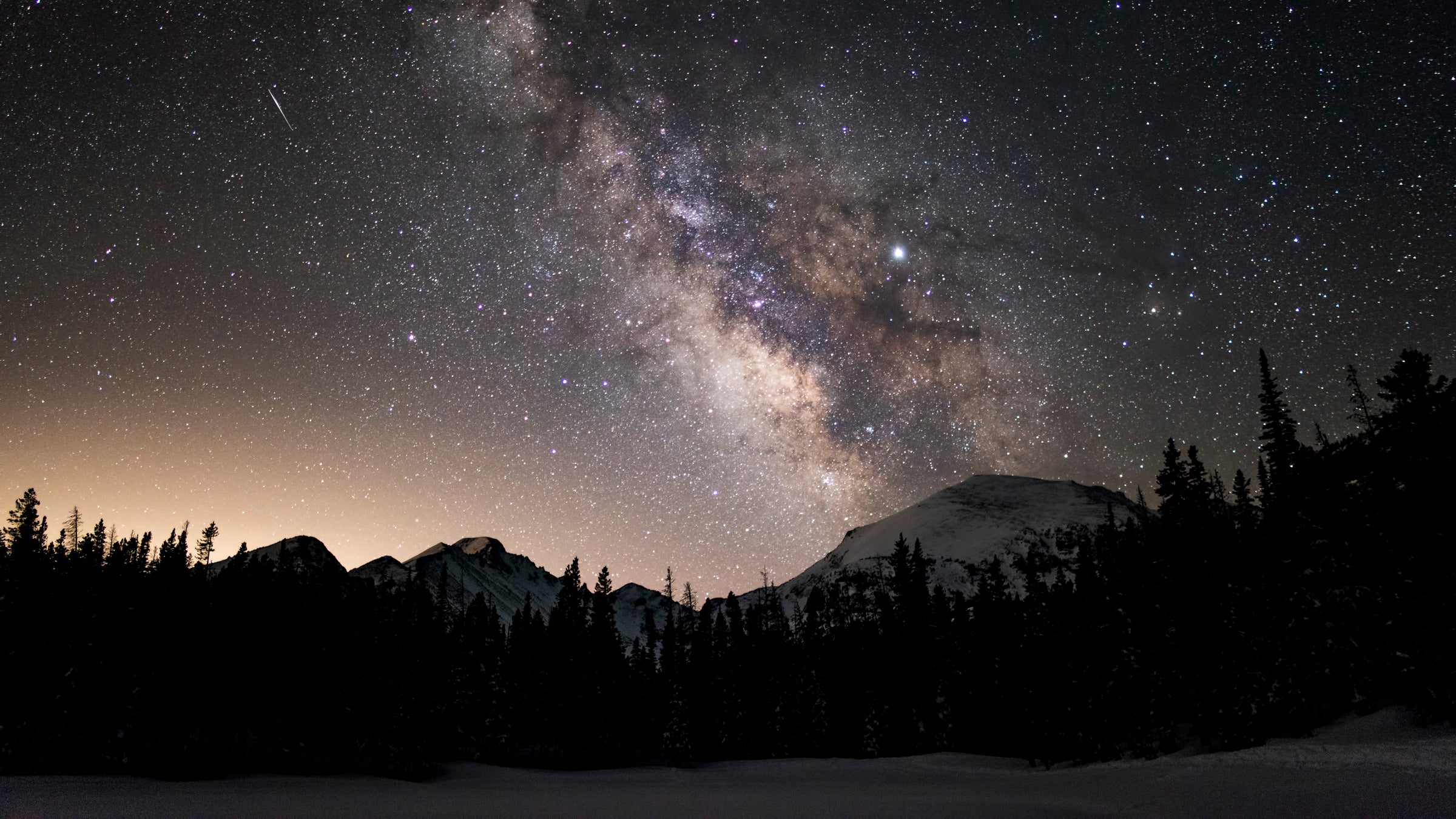 The Persed meteor shower streaks across the milky way above Rocky Mountain National Park